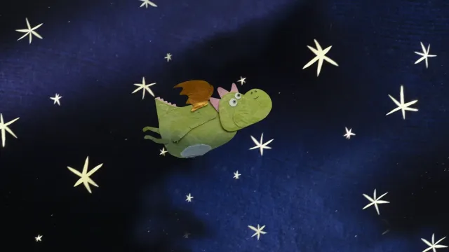Frame di un corto animato in stop motion, si vede un draghetto di carta che vola nel cielo stellato